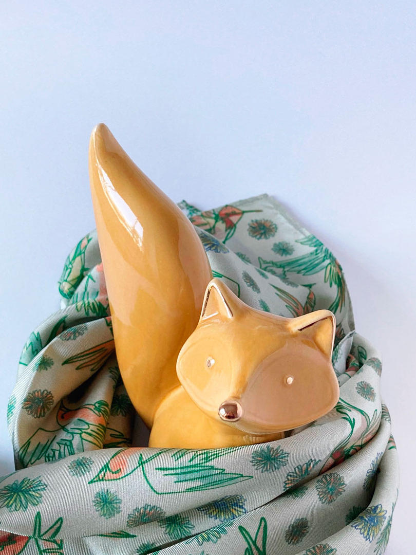 green silk scarf with birds next to decorative fox