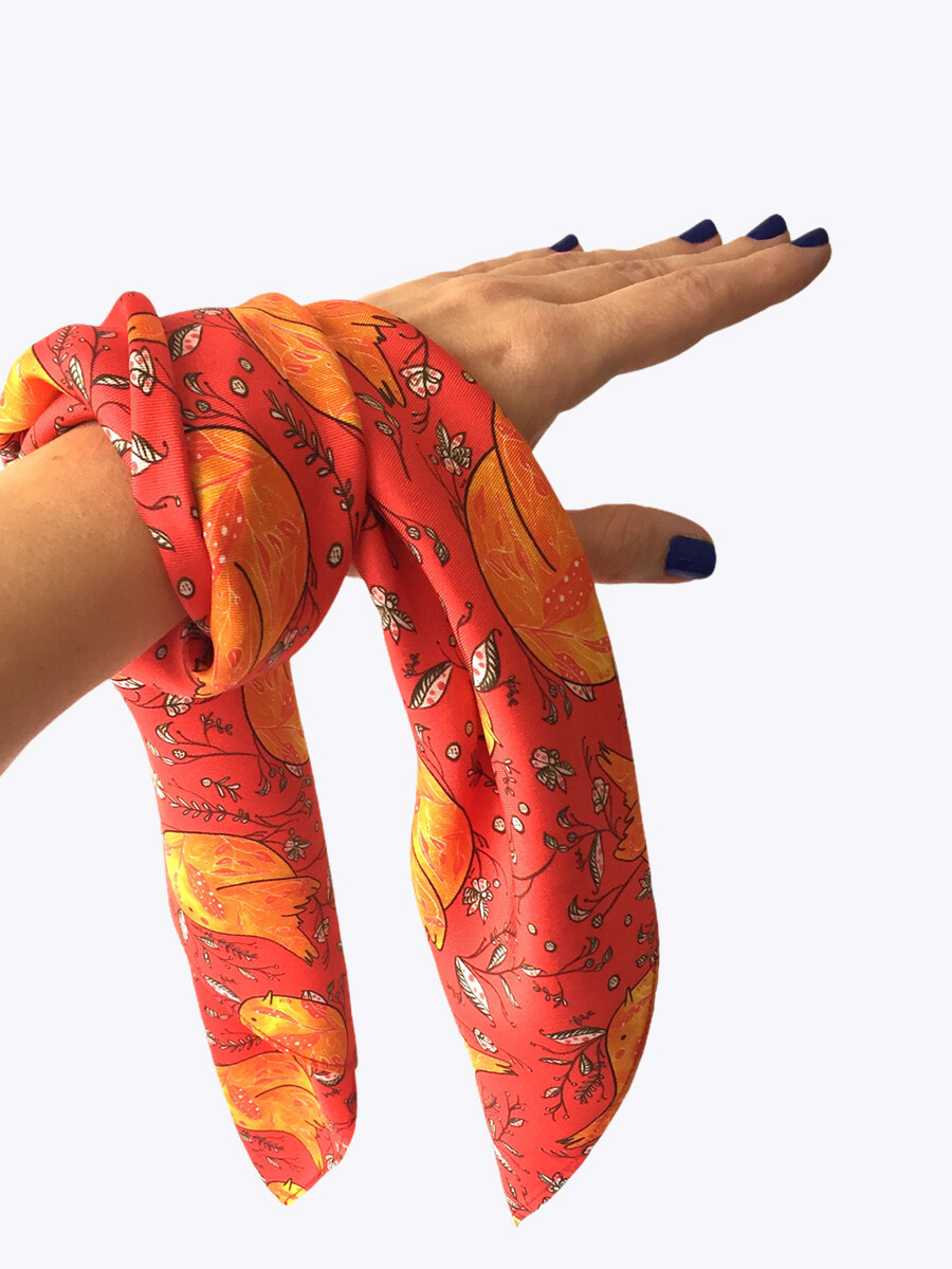 hand holding red silk scarf with illustrated print of birds and flowers