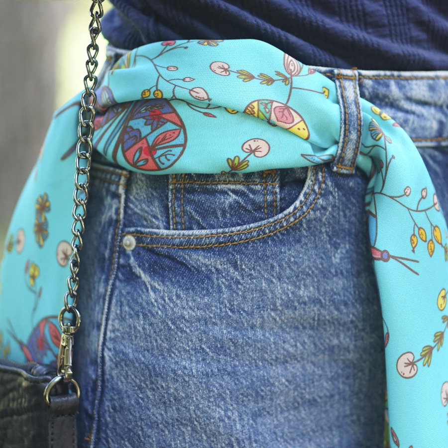 Pañuelo de seda turquesa anudado a la cintura sobre falda vaquera