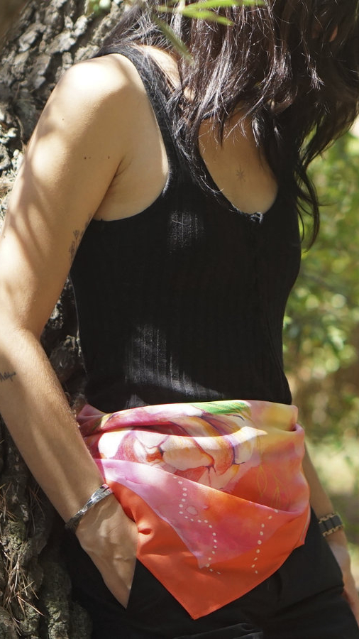 Natural orange silk scarf knotted at the waist of a woman dressed in black