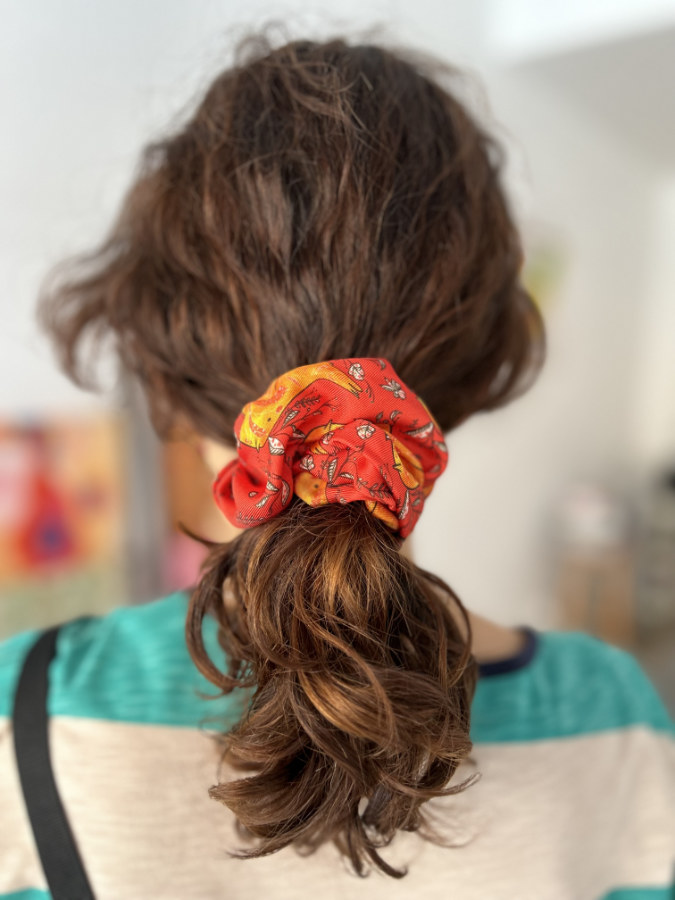 mujer de pelo rizado corto con coletero de seda rojo