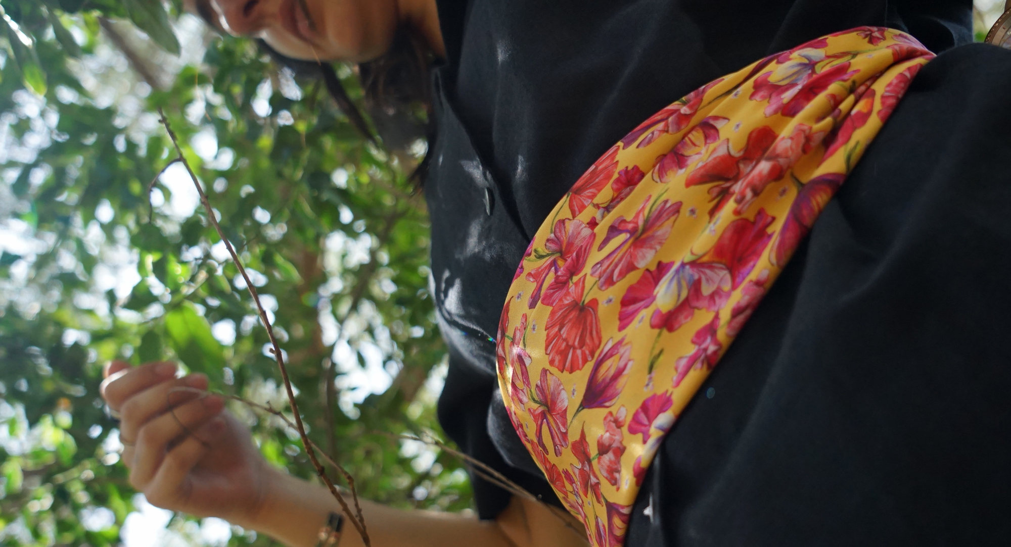detail of a silk scarf with flowers as a belt with black clothes with a nature background