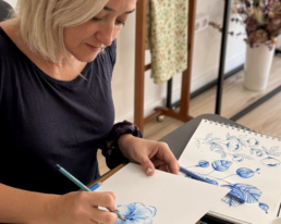 artista Estela Rivero pintando una flor azul en su estudio showroom