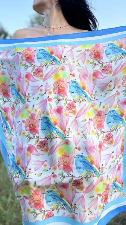 young woman in nature holding natural silk scarf with bird and flower motifs