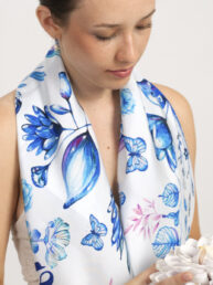 pañuelo de seda natural en azules sobre blanco Big Love al cuello de una mujer joven con una flor en la mano