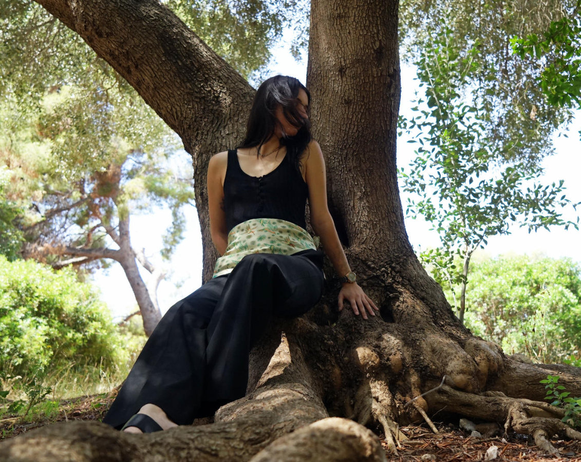 Printed green silk scarf used as a belt over black clothing