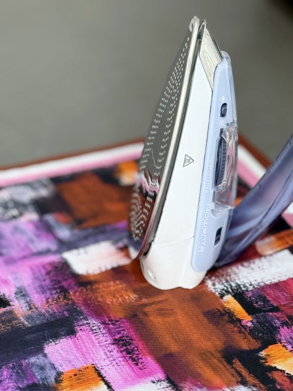 plancha posada sobre pañuelo de seda estampado en colores granates y rosas